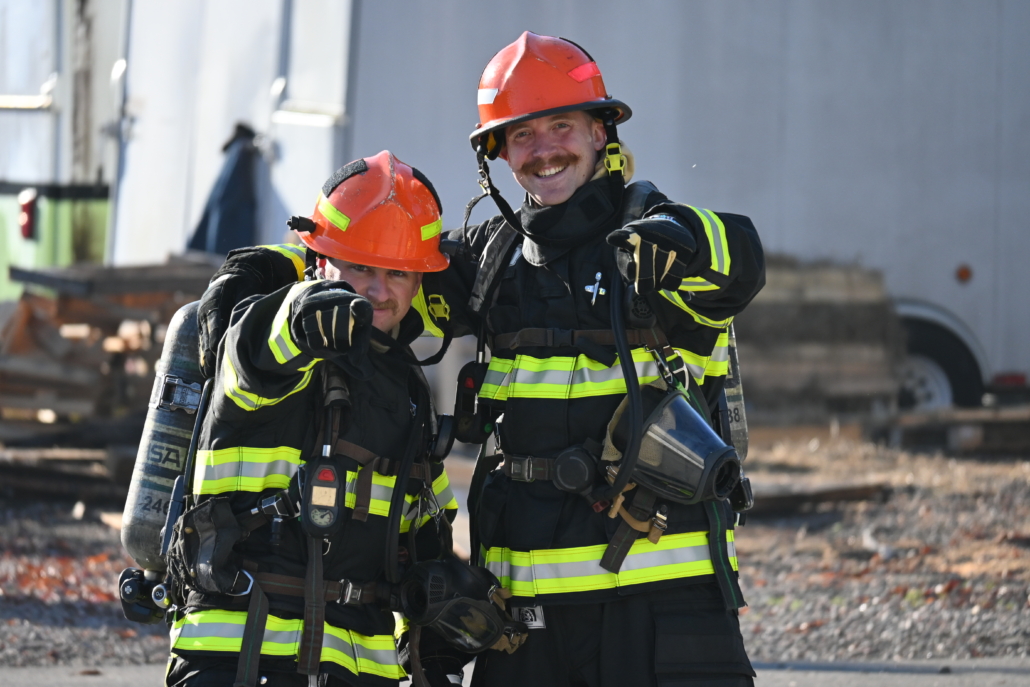 Two firefighters smiling after a fire extinguished.